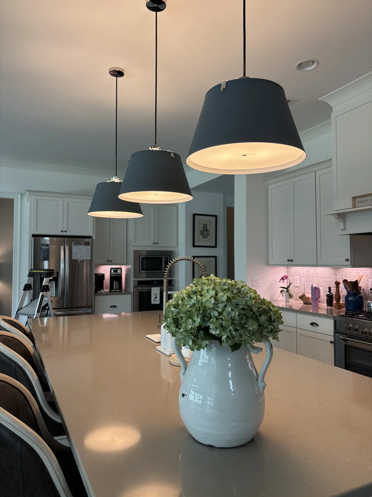 Row of pendant lights over a kitchen island, seen from the end of the island